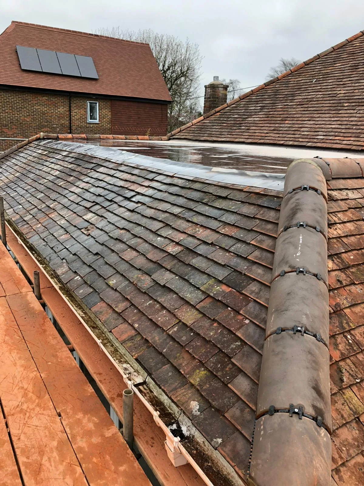New ridge tiles being set on an old clay tile roof