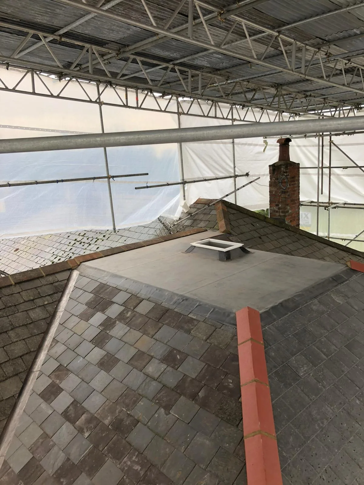 Finished slate roof with red clay ridge and brick chimney